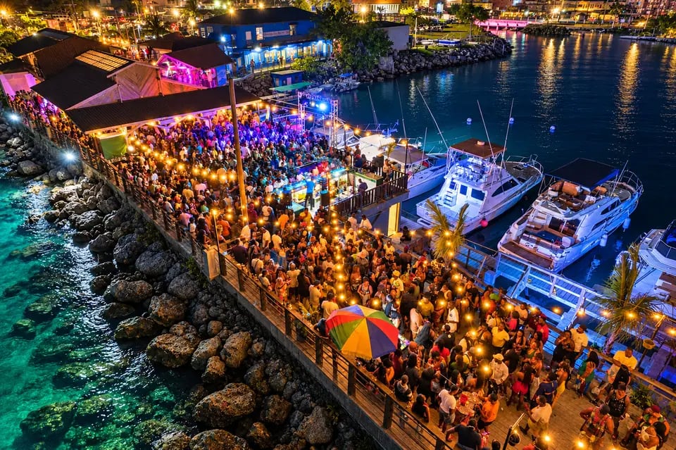 Festa noturna lotada em píer iluminado à beira-mar