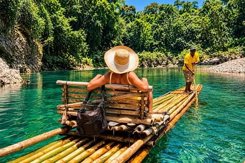 Balsa de bambu conduzida por balseiro em rio cercado de mata