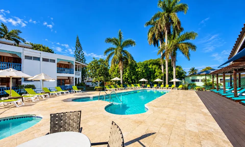 Área da piscina do Toby's Resort com coqueiros e céu azul